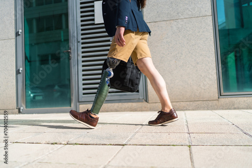 Unrecognizable businessman with prosthetic leg walking along street