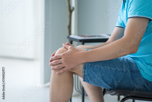Knee pain  man suffering from ache and doing self-massage at home