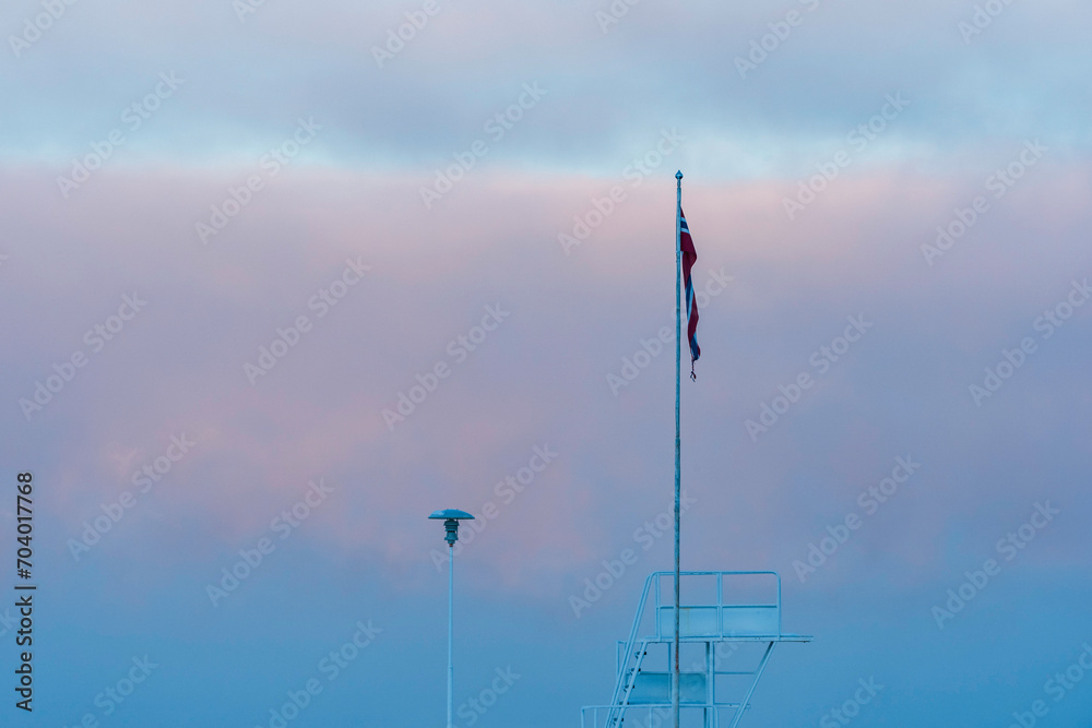 The Panengen jetty with the Norwegian flag and the diving tower in front of the Lake Mjosa mist in January. The Panengen jetty with the Norwegian flag and the diving tower in front of the Lake Mjosa mist in January.
