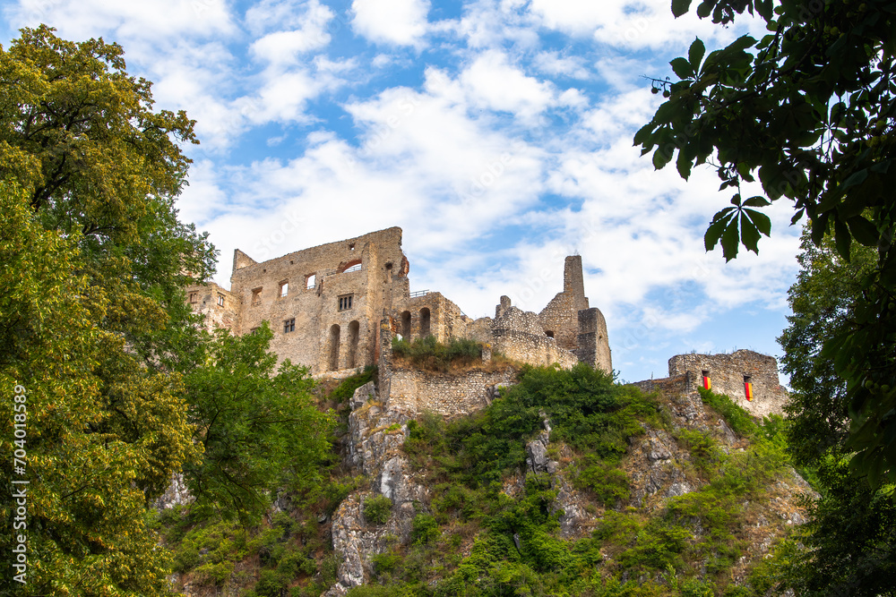 Beckov Castle, standing on a high cliff, surrounded by greenery.