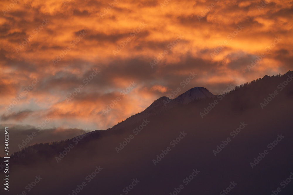 beautiful sunrise with orange sky in the mountains at a winter morning