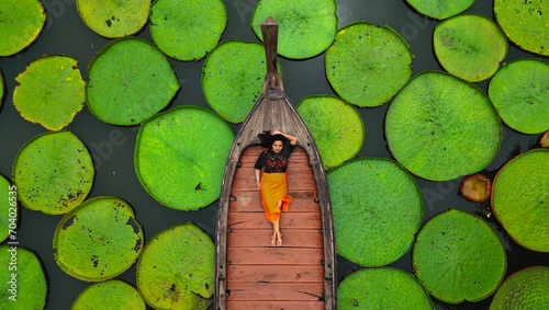 Aerial view of an Asian woman relaxing on a boat outdoor on Lotus pond at Phuket Thailand photo