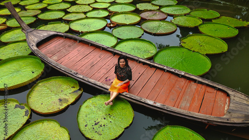 Girl sitting on a long tail boat surrounded by Queen Victoria water lilies in Phuket Thailand photo