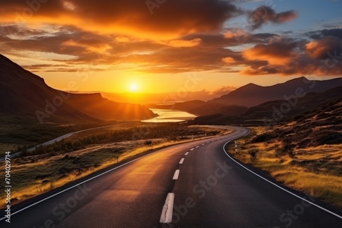 the sun is setting over the mountains and a road in the foreground is a body of water with a body of water in the middle of water in the distance. © Shanti