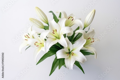  a bouquet of white lilies with green leaves on a white background with copy - space for text or image, top view of a bouquet of white lilies with green leaves on a white background. © Shanti