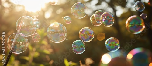 Adults joyfully blow colorful bubbles with a wand, enjoying the excitement of fragile, soapy balloons. photo