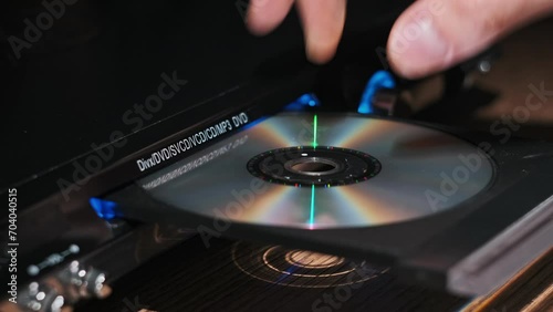 DVD compact disc is inserted into the player. Male hand loads CD into a CD player tray close-up. Music, movies, or data recorded on a laser optical information storage medium. Loading Compact Disc photo