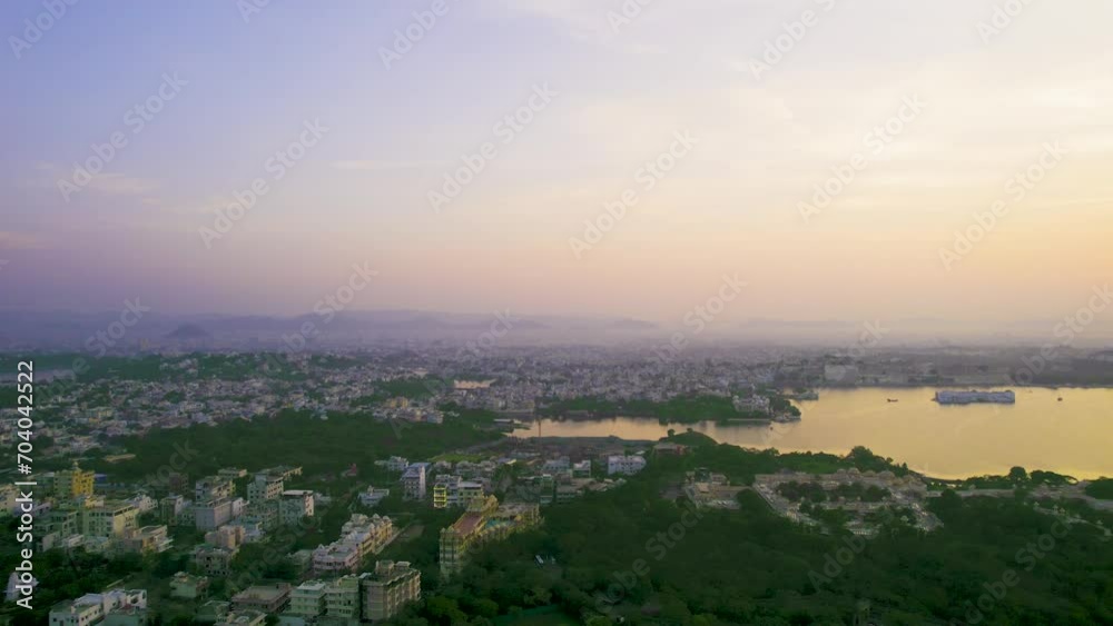 aerial drone shot panning at sunrise over cityscape of udaipur rajasthan India towards lake pichola fateh sagar with sun rising behind aravalli mountains in this tourist spot aerial drone shot panning at sunrise over cityscape of udaipur rajasthan India towards lake pichola fateh sagar with sun rising behind aravalli mountains in this tourist spot