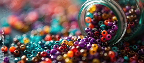 Rainbow hair beads dropped from a glass jar containing assorted pony beads. photo
