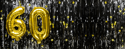 Gold foil balloon number number 60 on a background of black tinsel decoration. Birthday greeting card, inscription sixty. Anniversary event. Banner. photo