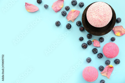Bath bomb with blueberry and floral petals on blue background
