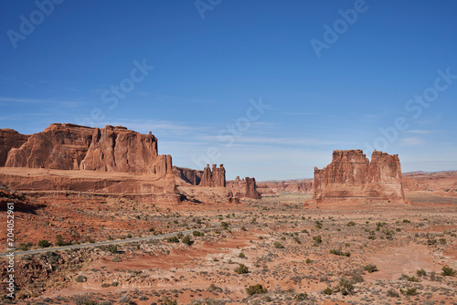 Road leads through the various monument looking rock formations, hoodos, and sparse desert of Arches National Park © Daniel