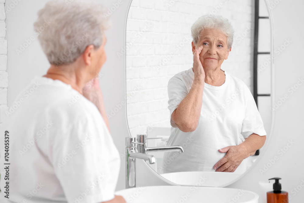 Fototapeta premium Senior woman looking in mirror at home