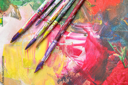 Dirty paint brushes on colorful background