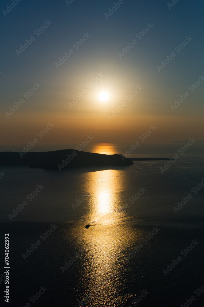 Quietly sunset at Santorini with a boat in the sunlight reflected in the water of aegean sea greece