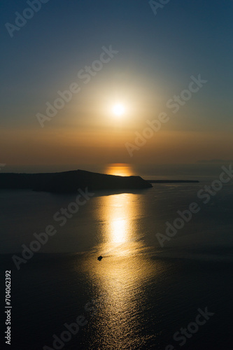 Quietly sunset at Santorini with a boat in the sunlight reflected in the water of aegean sea greece