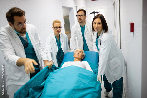 Professional team of surgeon, doctors and nurse moving unconscious patient on a gurney to the emergency operating room. photo
