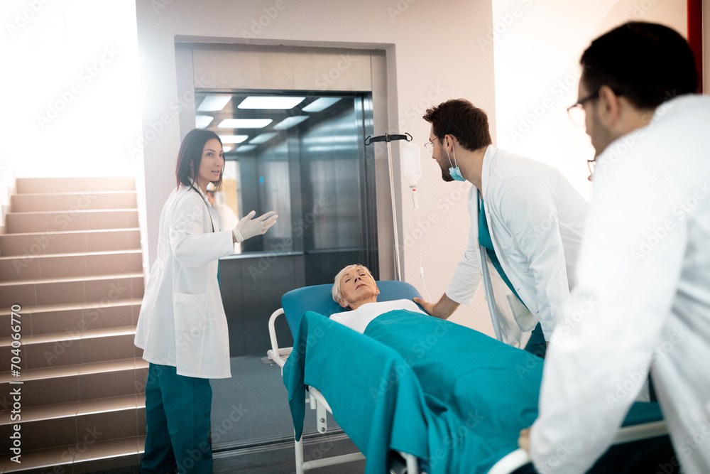 Obraz premium Medical team rushing sick elderly woman lying on medical gurney in hospital elevator.