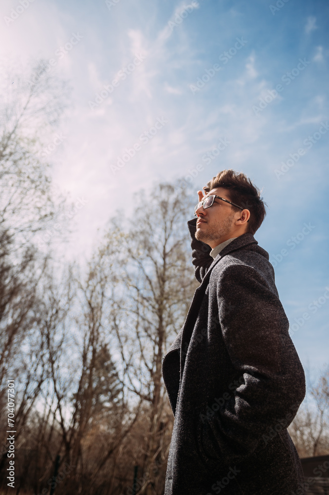 The photo shows a man wearing glasses, standing outdoors in a winter se The photo shows a man wearing glasses, standing outdoors in a winter se