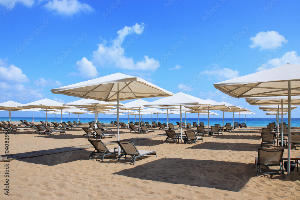 Beautiful tropical scenery. Sun beds, loungers, umbrella. Sea. Resort hotel. Rows of folded beach umbrellas and empty sunbeds on the beach. Leisure concepts. Vacation and summer concept. Travel 