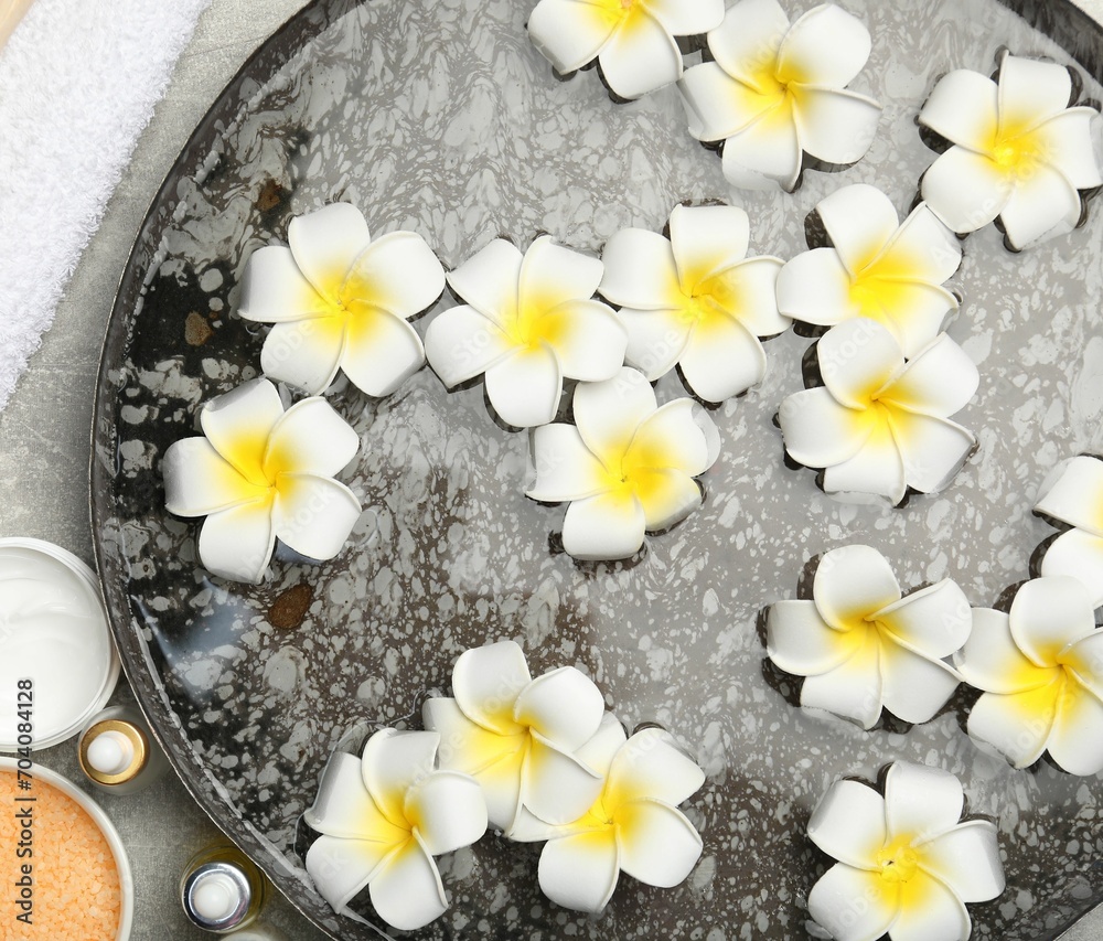 Bowl of water with flowers and different spa supplies on light grey table, flat lay Bowl of water with flowers and different spa supplies on light grey table, flat lay