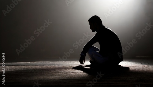 silhouette of sad man crouching on the ground in the dark