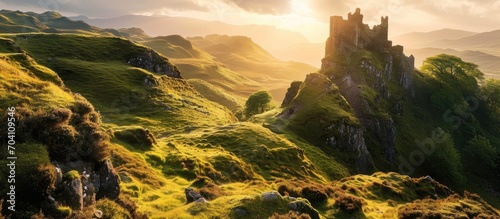 The Fairy Glen's Castle Ewan, a hilltop tourist spot on the Isle of Skye, Scotland, bathed in golden light during sunrise or sunset.