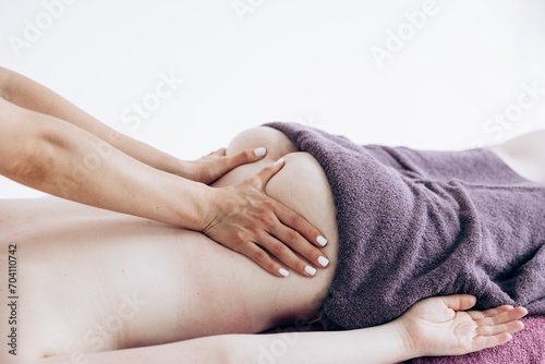 A girl in a pink uniform gives a massage to a woman. Back exercises, spa treatments