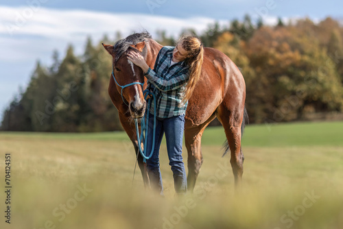 A young woman cuddle with her bay brown trotter horse in autumn outdoors
