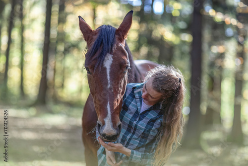 A young woman cuddle with her bay brown trotter horse in autumn outdoors