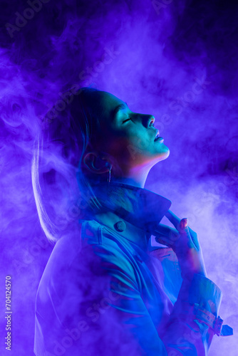 Young woman in neon multi-colors light on smoke, steaming background. stylish