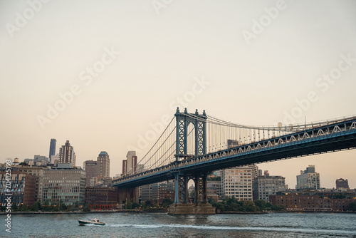 Manhattan Bride and Brooklyn view in summer during Golden Hour with boats moving on the Hudson River