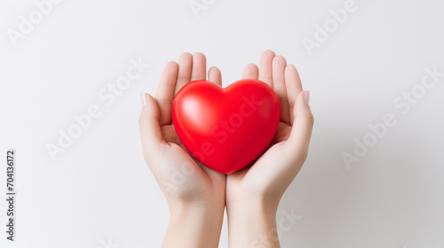 Hands hold a red volumetric heart on a white background. Heart close up.