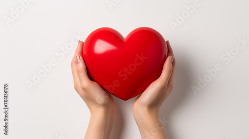 Obraz na płótnie Hands hold a red volumetric heart on a white background. Heart close up. w salonie