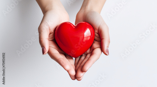 Obraz na płótnie Hands hold a red volumetric heart on a white background. Heart close up. w salonie