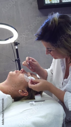 Work of professional stylist, lengthening women's eyelashes. Cosmetic procedures . Master combs client's eyelashes after lamination. Concept of beauty and fashion. 4k footage.