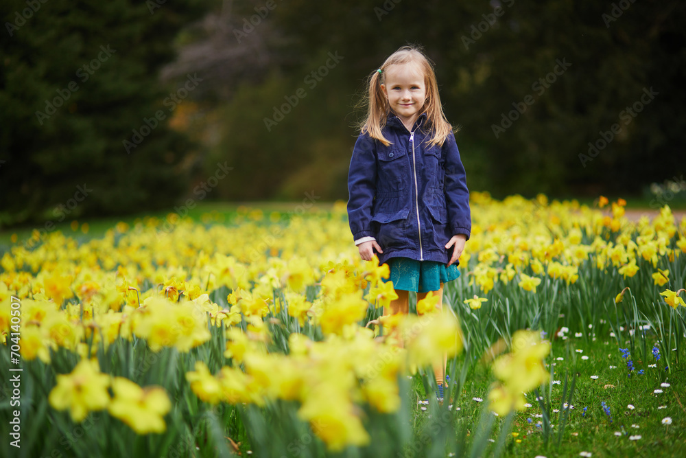 Adorable preschooler girl enjoying nice spring day in park during jonquils blooming season Adorable preschooler girl enjoying nice spring day in park during jonquils blooming season