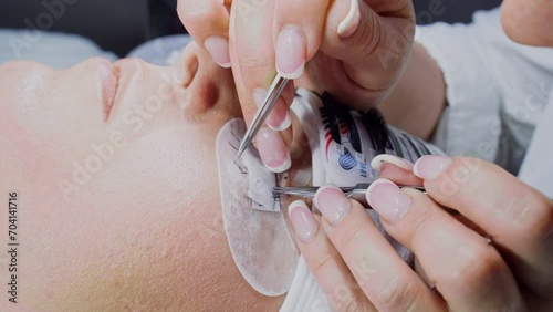 Close-up of female hands of master cosmetologist, stylist, who does procedure of eyelash extension to client. Beauty salon. Concept of beauty and fashion. Professional work of stylist. 4k footage