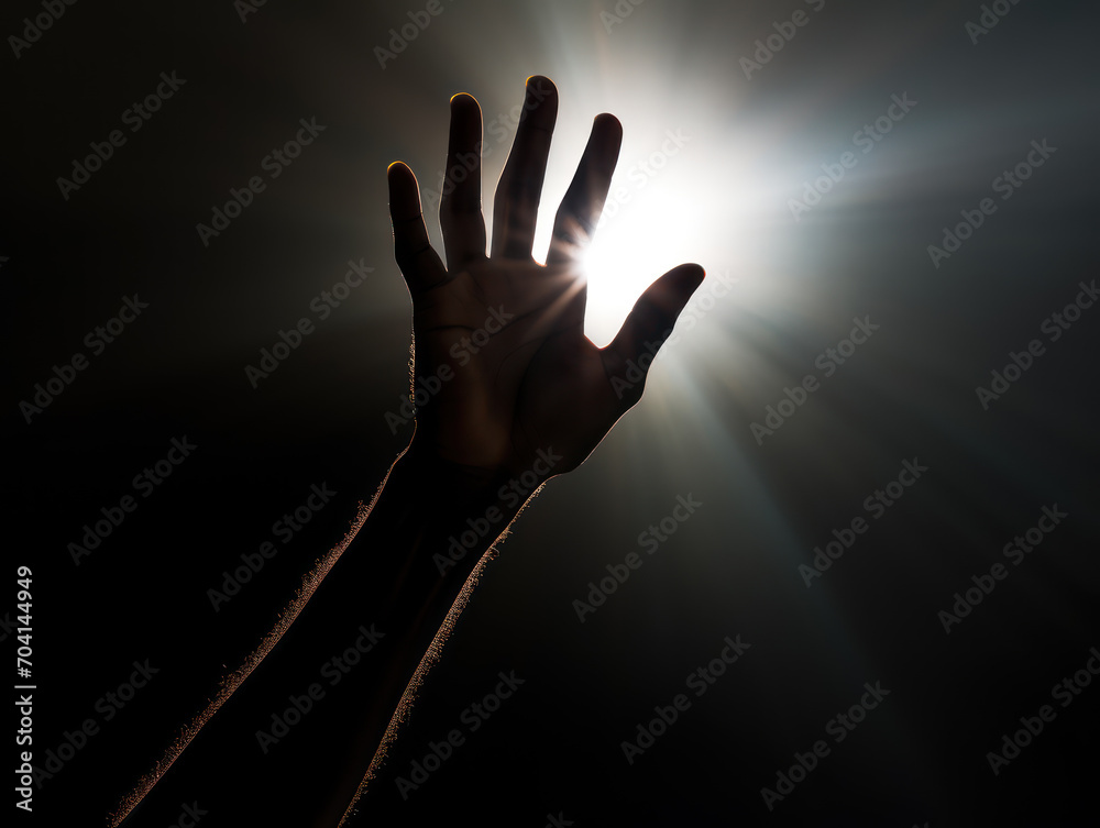 Silhouette of a hand reaching upwards seeking help from a light source