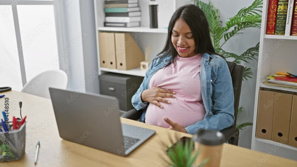 Expecting young business woman, smiling and touching belly while enjoying a successful video call at the office Expecting young business woman, smiling and touching belly while enjoying a successful video call at the office