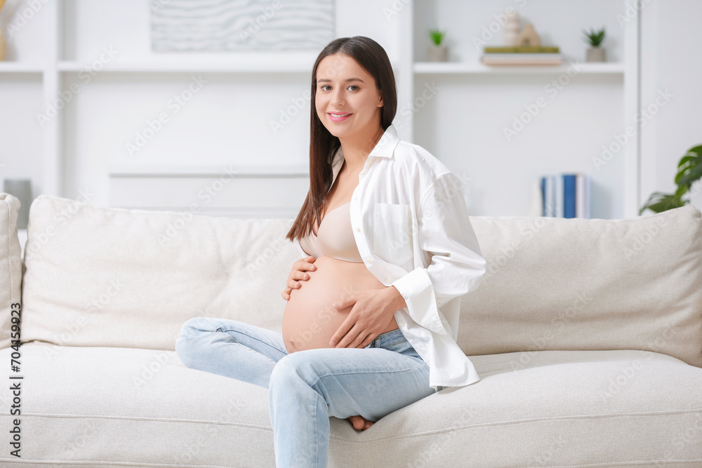 Beautiful pregnant woman sitting on sofa at home Beautiful pregnant woman sitting on sofa at home