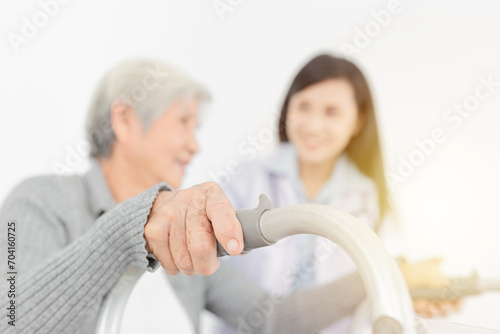 close up hand, walk training and rehabilitation process, old asian stroke patient learning to uses walker with female asian doctor in hospital, elderly healthcare promotion