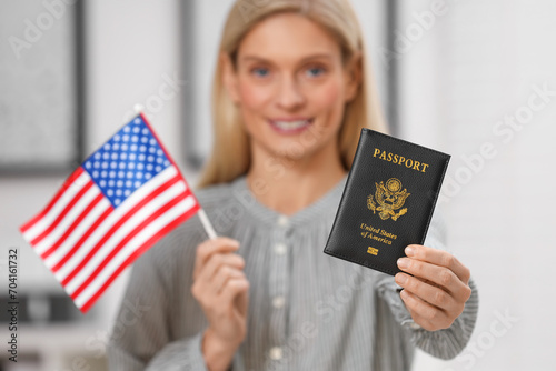 Immigration. Happy woman with passport and American flag indoors, selective focus photo