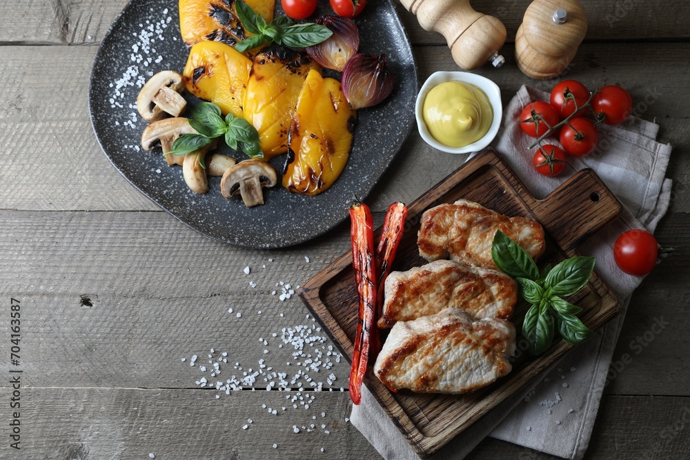 Delicious grilled meat and vegetables served on wooden table, flat lay. Space for text