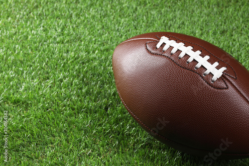 Leather American football ball on green grass, closeup. Space for text