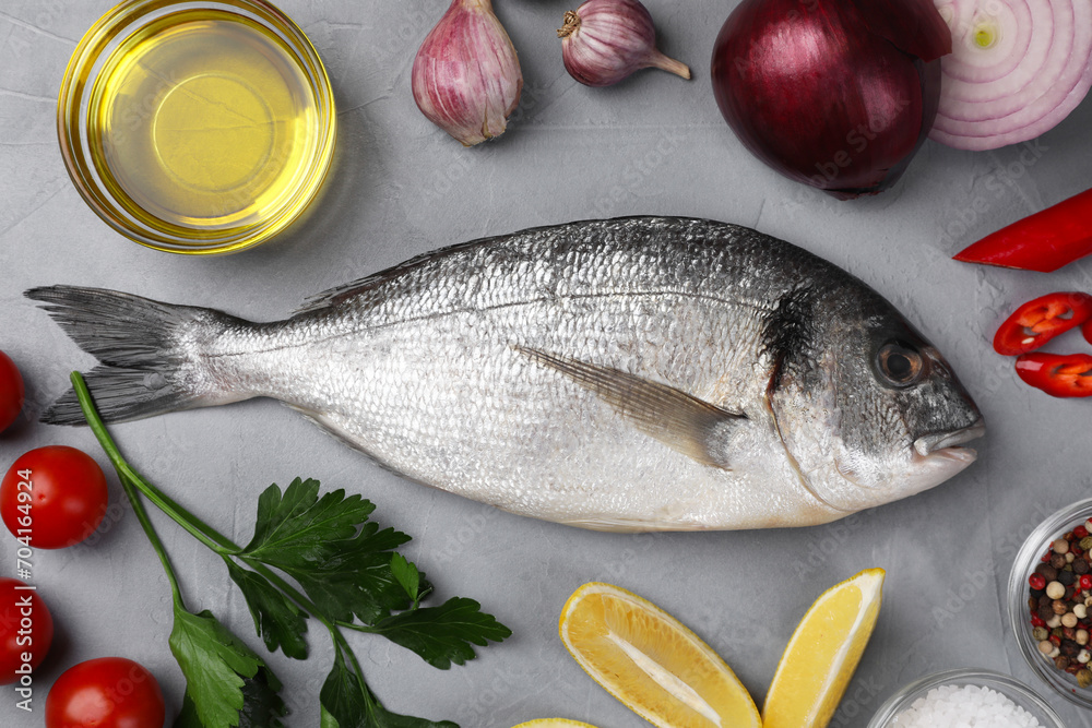 Flat lay composition with raw dorado fish and vegetables on grey table Flat lay composition with raw dorado fish and vegetables on grey table