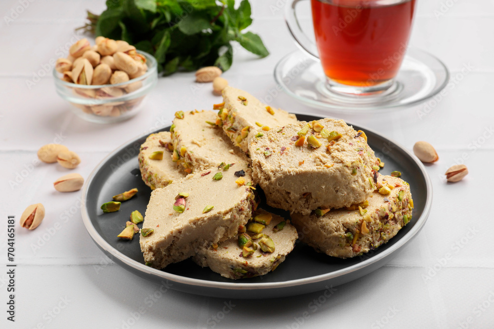 Tasty halva with pistachios served on white tiled table, closeup Tasty halva with pistachios served on white tiled table, closeup