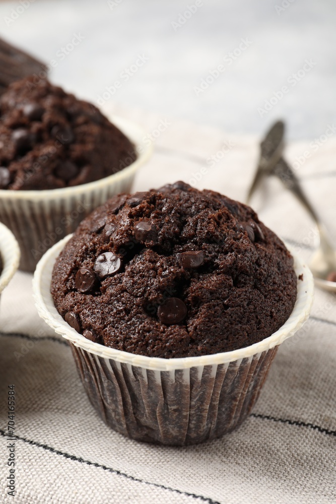 Tasty chocolate muffins and cloth on table, closeup Tasty chocolate muffins and cloth on table, closeup