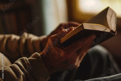 Close up of senior man reading book while sitting in vintage chair at home