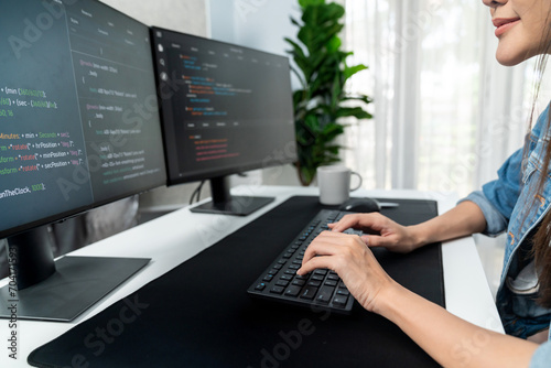 Young Asian in IT developer creating with typing online information on pc with coding program data of website application, wearing jeans shirt. surrounded by safety analysis two screens. Stratagem.